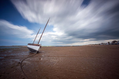 Boat moored on beach against sky during sunset