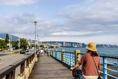 Rear view of woman on pier over sea against sky