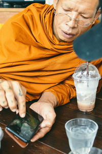 Midsection of man holding drink sitting on table