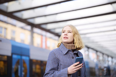 Woman using cell phone at tram stop