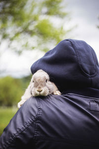 Back view of man holding bunny on his shoulder