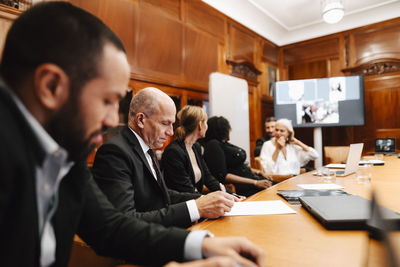 Male financial advisor signing agreement during meeting with colleagues in board room