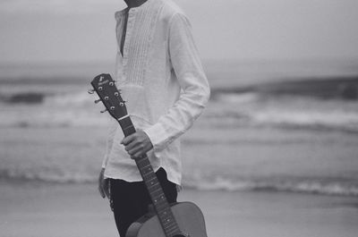 Midsection of man playing guitar