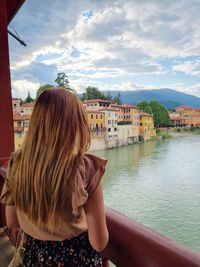 Rear view of woman in canal against cityscape