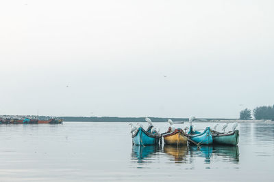 Fishing boats moored in lake against clear sky