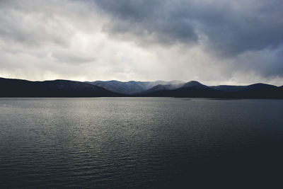 Scenic view of lake by mountains against sky