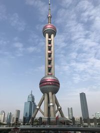 Communications tower in city against sky