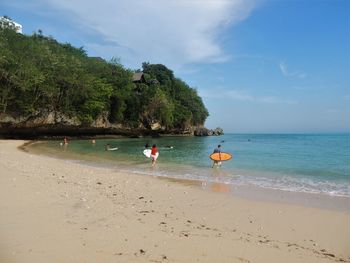 People at beach against sky