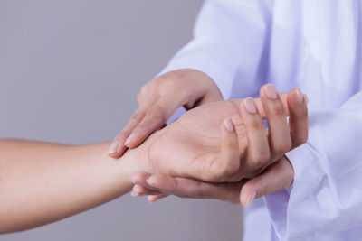 Midsection of doctor taking patient pulse at hospital