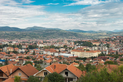 Aerial view of townscape by mountains against sky