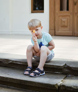 Boy looking away while sitting on door