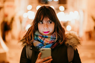 Portrait of woman holding smart phone during winter