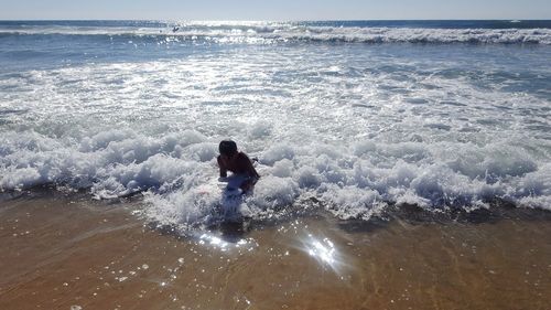 High angle view of boy playing in waves at beach during summer