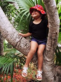 Happy young woman standing on tree trunk