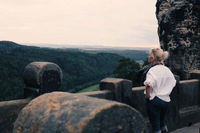 Woman standing looking at mountain against sky