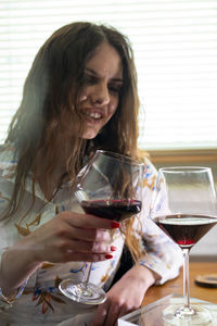 Young woman holding drink while sitting on table