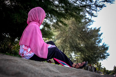 Side view of girl sitting on tree