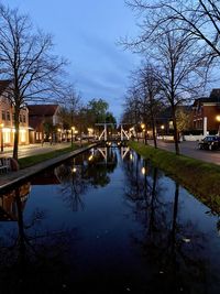 Canal amidst buildings against sky at dusk