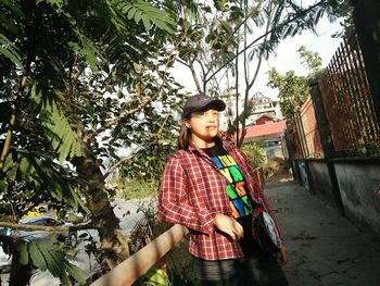 Young woman standing by tree against plants