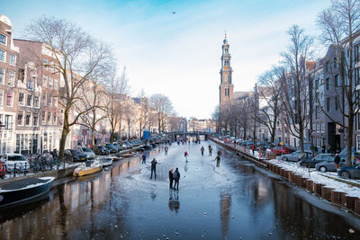 Canal amidst buildings in city against sky