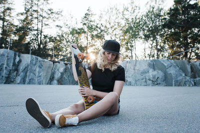 Skater girl looking thoughtful holding her board at sunset