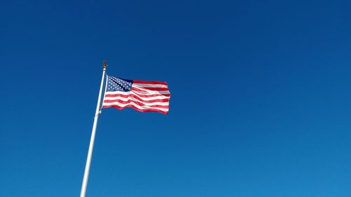 Low angle view of flag against clear blue sky