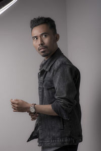 Portrait of young man standing against wall