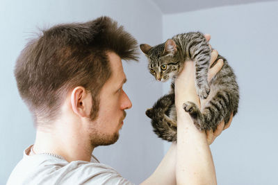 Man plays with a kitten. hugs him and kisses him