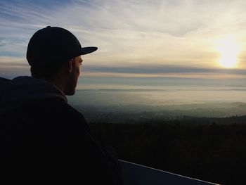 Man looking at scenic view of landscape against sky during sunset