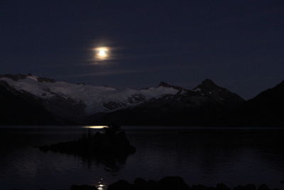 Scenic view of lake and mountains against sky at night