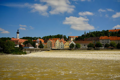 Buildings by river against sky