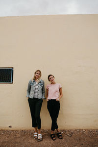 Full length portrait of woman standing against wall