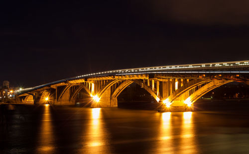 Illuminated bridge over river at night