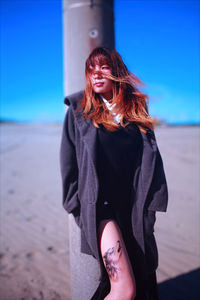 Beautiful woman wearing sunglasses at beach against sky