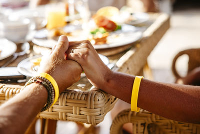 Cropped image of heterosexual couple holding hands at table in resort