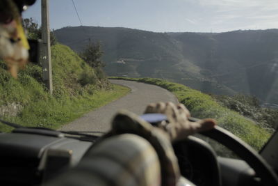 Close-up of person driving car on road against mountain