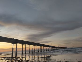Bridge over sea against sky during sunset