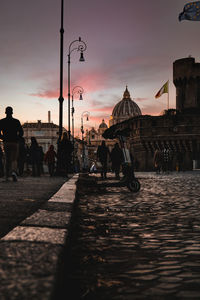 People walking on street in city at sunset