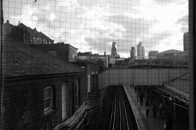 Railroad tracks in city against sky