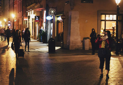 People walking on illuminated street at night