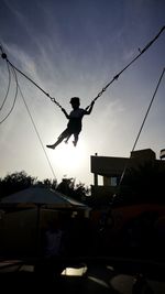 Silhouette man and rope against sky during sunset