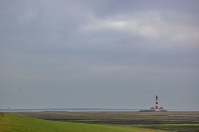 Lighthouse on land by sea against sky