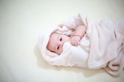 High angle portrait of baby boy lying on bed