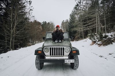 Man sitting on snow covered car