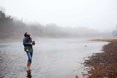 Full length of man in lake against sky during winter