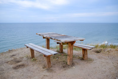 Deck chairs on beach by sea against sky