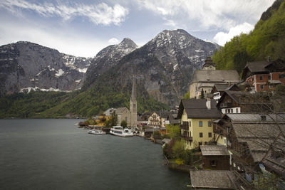 Houses by lake and buildings in town against sky