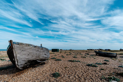 Abandoned boats moored on beach against sky