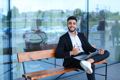 Portrait of smiling businessman sitting on bench outdoors