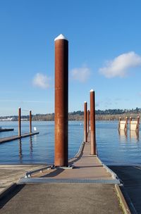 Wooden posts on pier over sea against blue sky